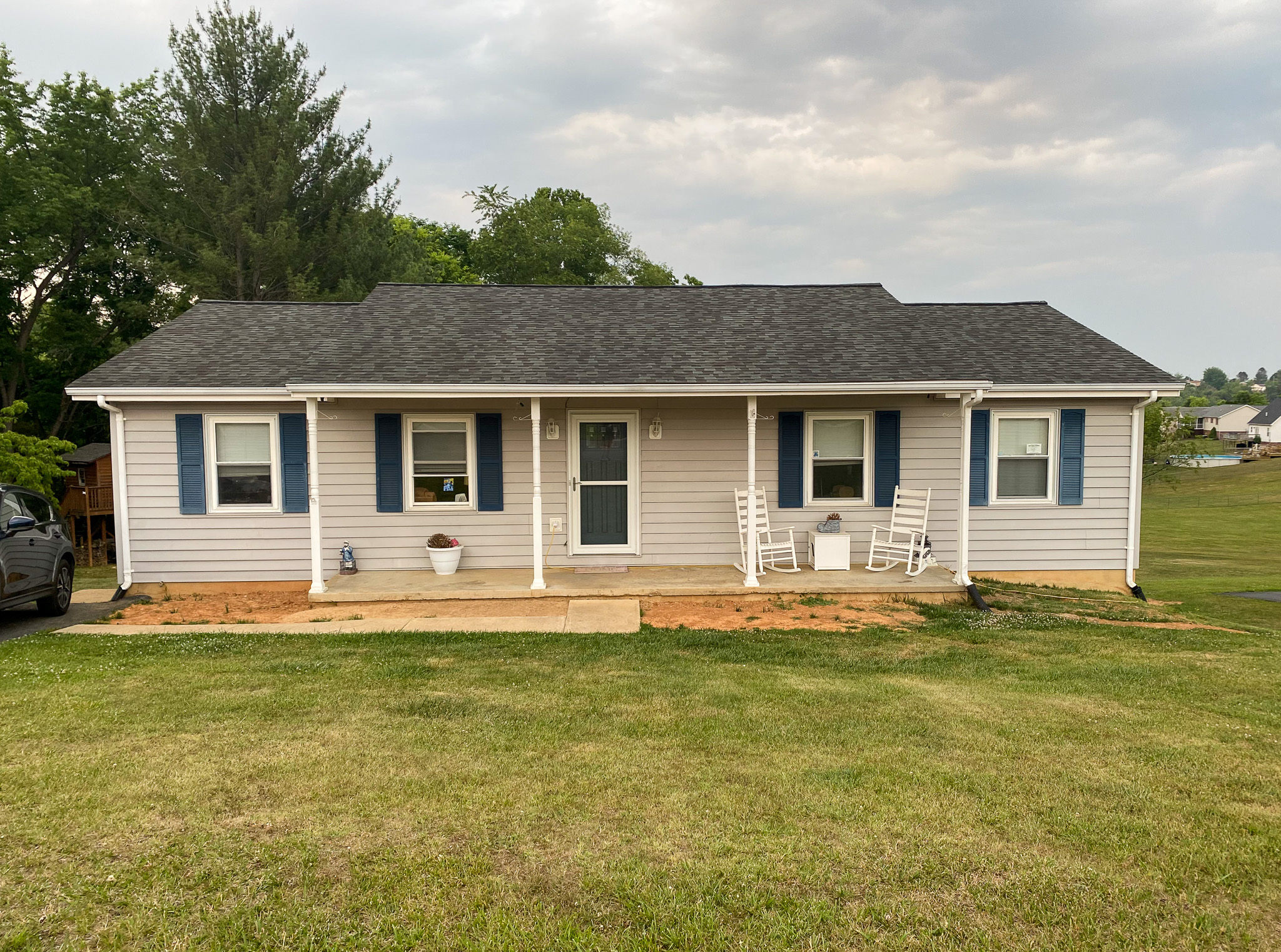 Single‑story light‑tan house with blue shutters, a small covered front porch with chairs, and a wide grassy yard belonging to Sponsored Residential Providers Karen and Rob Robertson in Verona, Virginia.