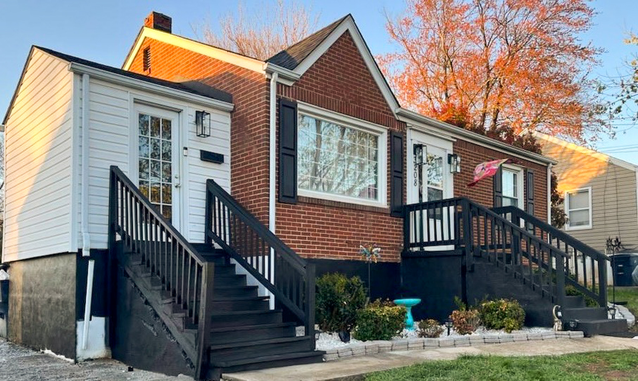 A brick house with two black-railed stairways, white siding accents, and neatly landscaped shrubs along the front belonging to Sponsored Residential Provider Claudia Davis in Roanoke, Virginia.
