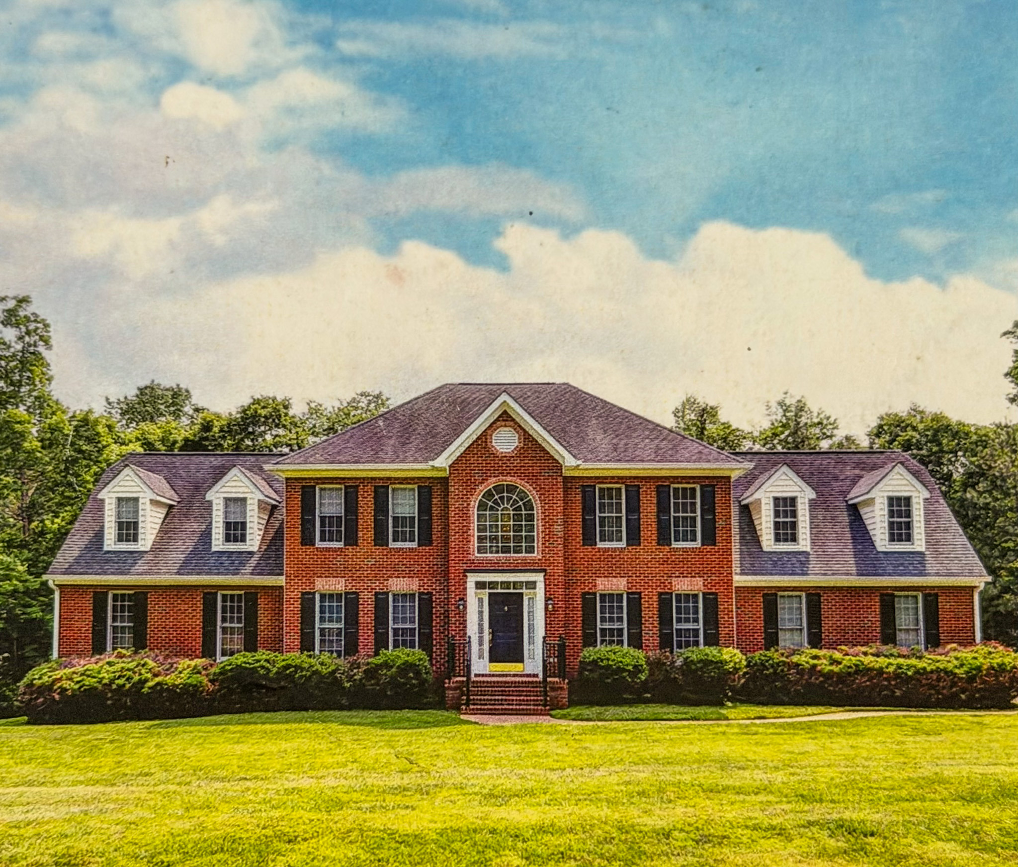 Two‑story brick house with dormer windows, arched entry window, and a landscaped front lawn belonging to Sponsored Residential Provider in Hampton Roads/Eastern Shore.