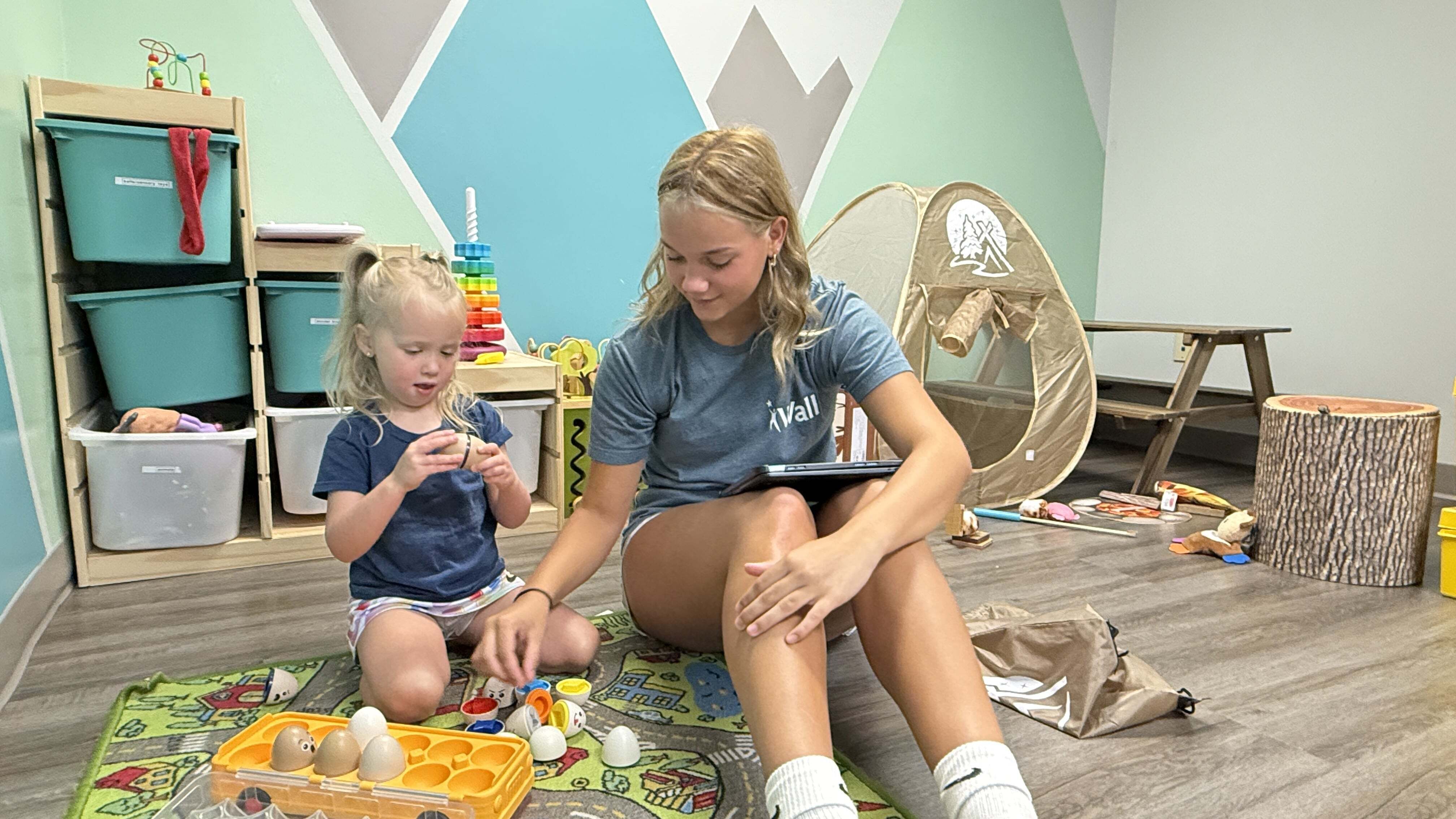Two girls playing with toys on the floor of one of Wall’s ABA therapy clinics