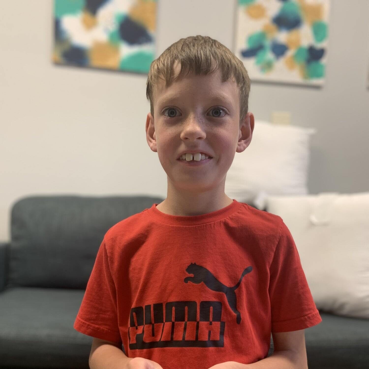 A young boy in a red shirt smiling at Wall Therapeutic Solutions