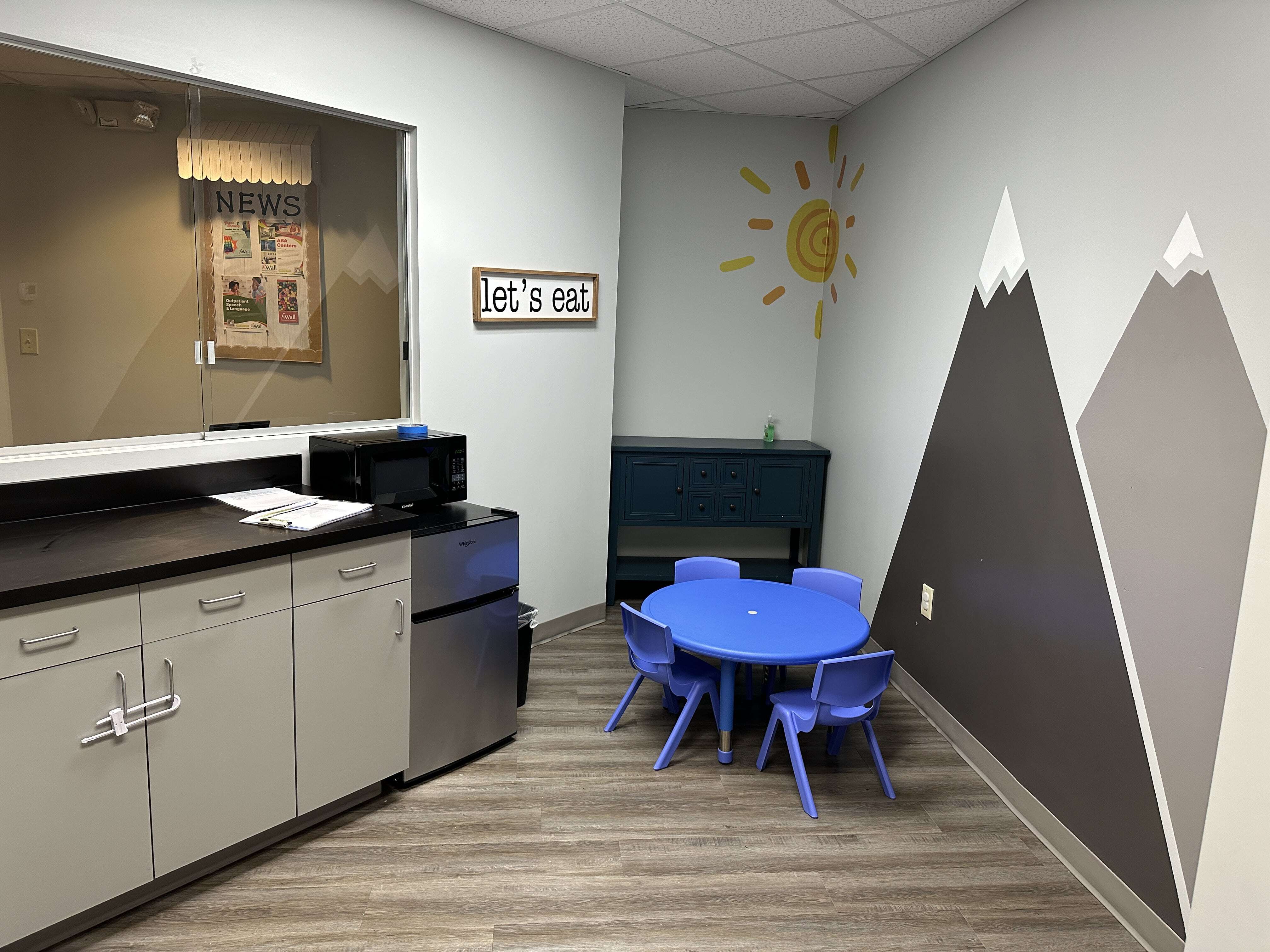 Small table with chairs and a counter area in the Christiansburg ABA Center, with mountains painted on the walls