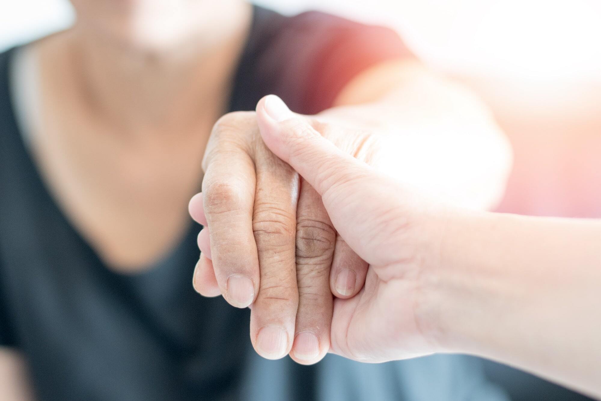Close-up photo of two hands gently holding each other