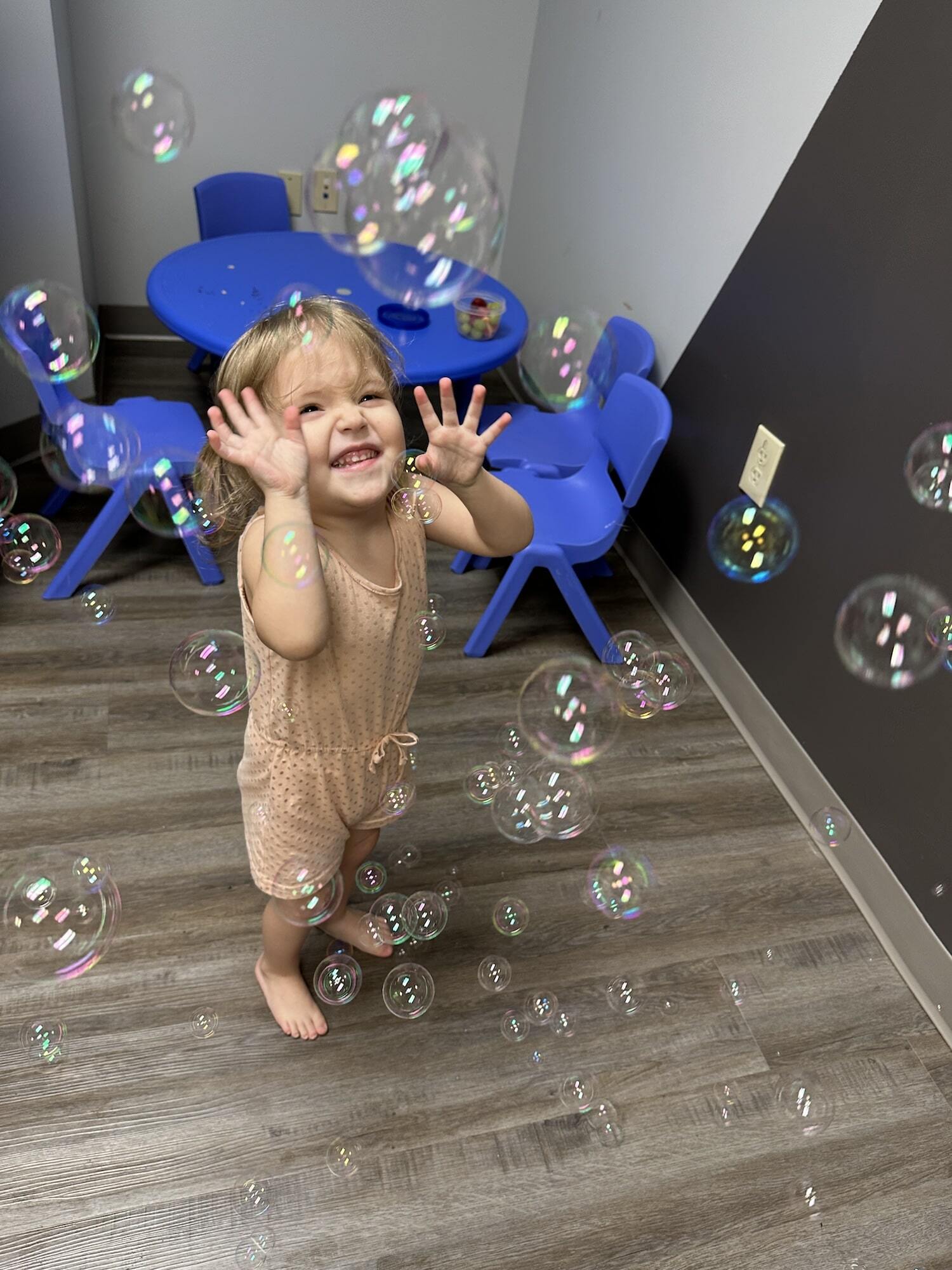 A young girl laughing while playing with bubbles at the ABA Center