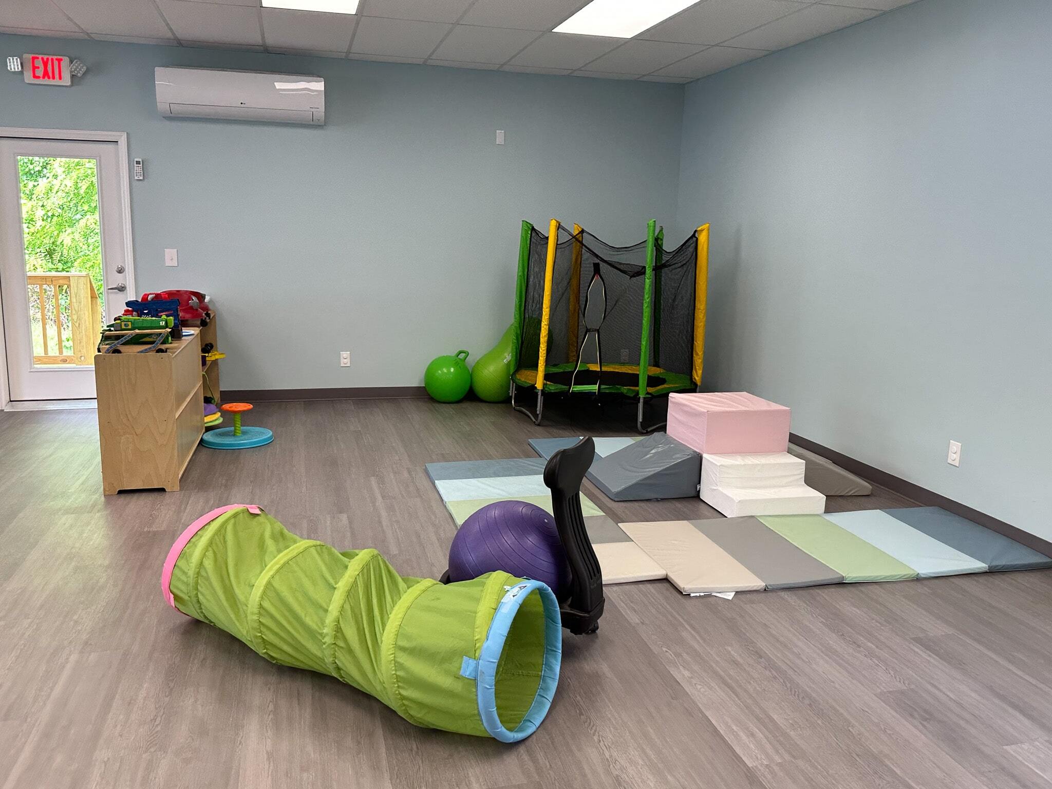 Toys and activities for children in the Salem ABA Center, featuring a trampoline, padded mats, and play equipment