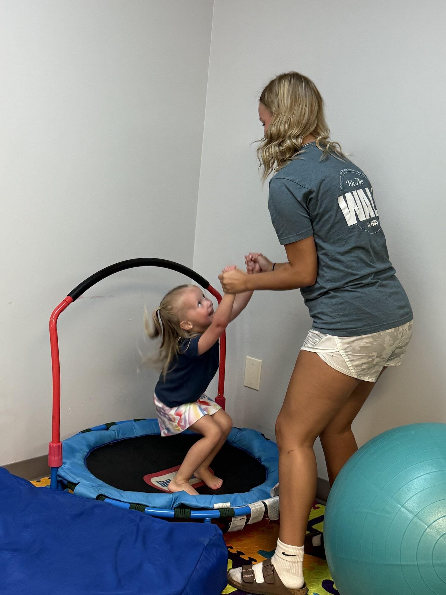 A child jumping on a trampoline with a Wall staff member at an ABA center